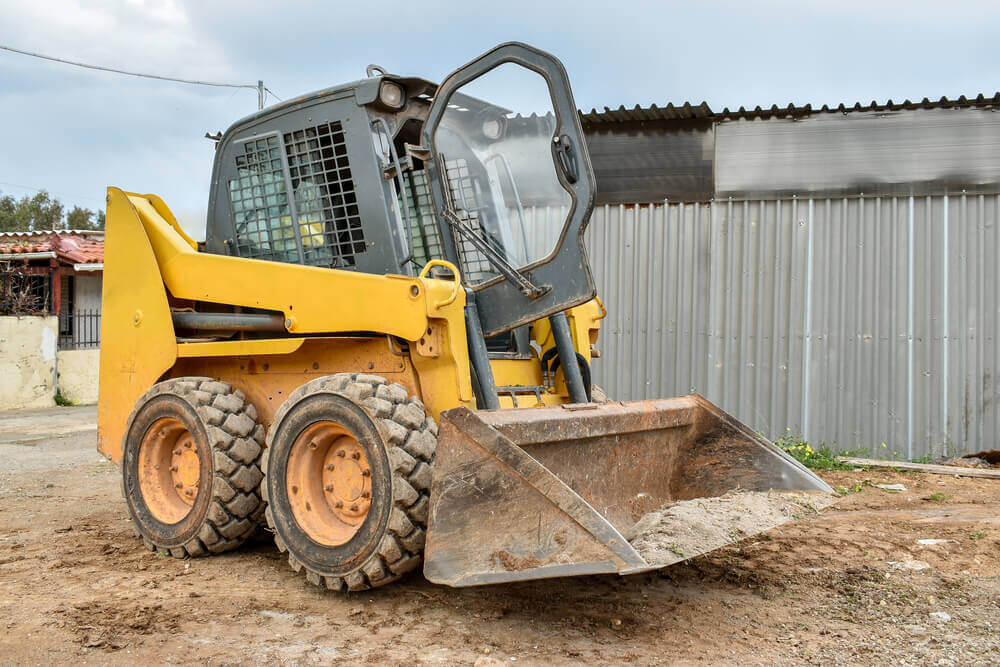 an image of an earthmoving Ballarat skid steer on a block of land with a fence behind it and the door open