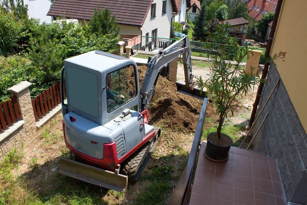 a mini earthmoving Ballarat excavator digging up a backyard next to a house